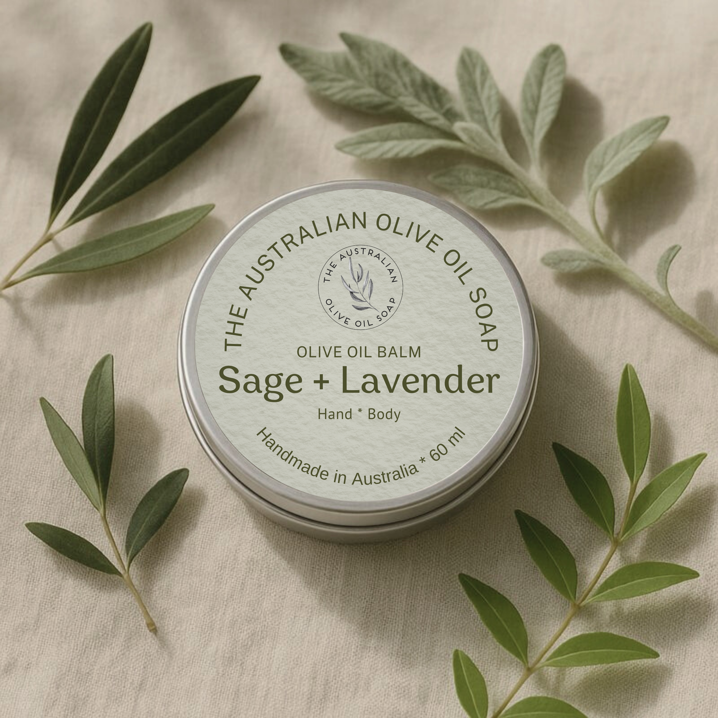 Sage + Lavender olive oil balm container with green leaves on a beige background
