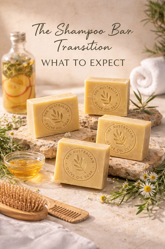 Four olive oil shampoo bars with The Australian Olive Oil Soap logo, styled on natural stone with rosemary, chamomile, apple cider vinegar, and wooden hair tools.