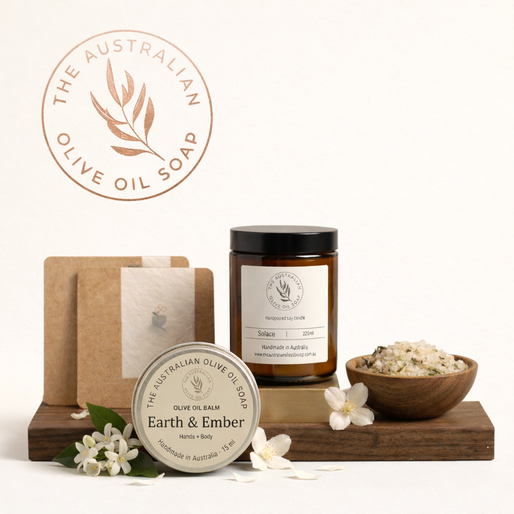 ustralian olive oil soap products including a bar, balm, and candle on a wooden stand with flowers.