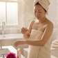 Woman applying rose beauty oil in a bathroom setting - The Australian Olive Oil Soap